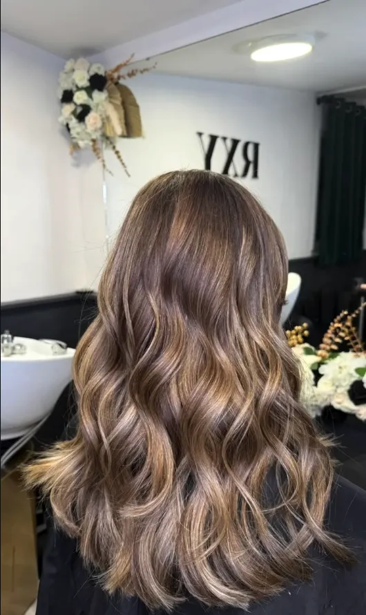 Brunette hair with caramel-toned waves, seen from behind in the studio