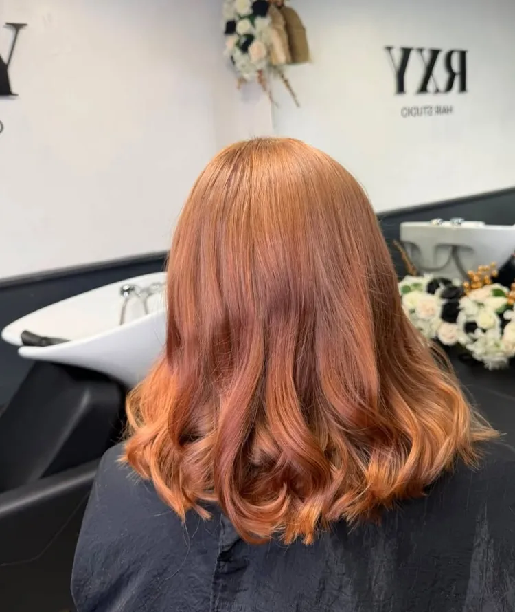 Long copper-toned waves, seen from behind in the studio
